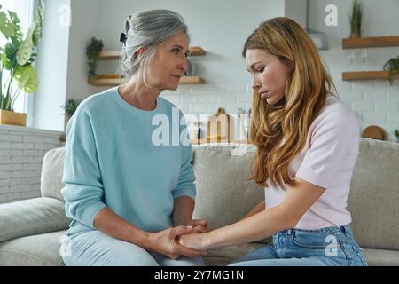 Jeune femme frustrée partageant des problèmes avec sa mère tout en étant assis sur le canapé à la maison Banque D'Images