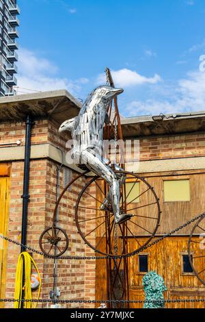 Sculpture cinétique de dauphin sur un vélo de penny farthing par Andrew Baldwin, Trinity Buoy Wharf, Londres, Angleterre Banque D'Images