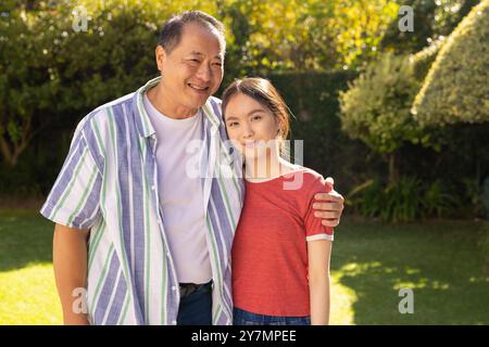 Sourire père asiatique et fille debout ensemble dans le jardin, profiter du temps en famille Banque D'Images