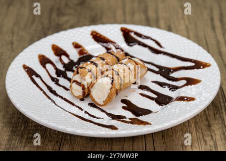 Un dessert italien traditionnel est servi, composé de cannoli arrosés de sirop de chocolat. Banque D'Images