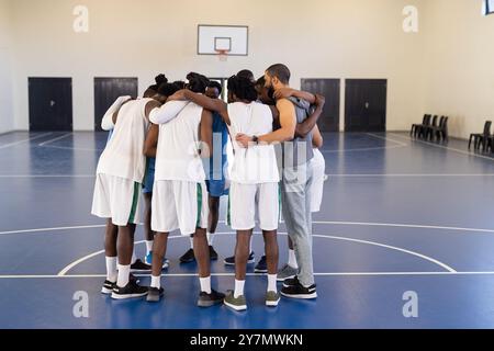 Se blottir ensemble, équipe de basket-ball se préparant pour le match dans un court couvert Banque D'Images