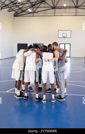 Équipe de basket-ball se blottissant sur le terrain, entraîneur donnant un discours de motivation avant le match, espace de copie Banque D'Images