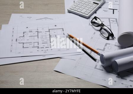 Différents dessins architecturaux, calculatrice, verres et crayons sur table en bois, gros plan Banque D'Images