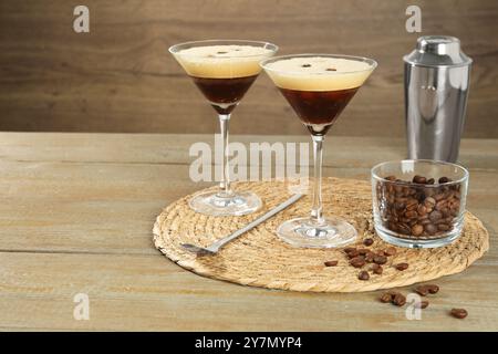 Verres de cocktail de café frais, shaker, haricots dans un bol et cuillère à mélanger sur une table en bois, espace pour le texte Banque D'Images