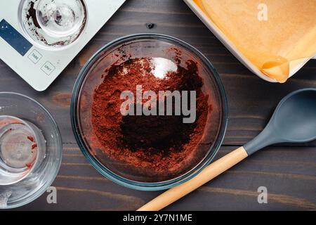 Poudre de cacao Dutched et noir et sucre dans un bol à mélanger : poudres de cacao, sucre et sel avant de mélanger entouré d'autres équipements de cuisson Banque D'Images