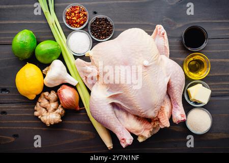 Poulet rôti vietnamien ingrédients : poulet entier entouré de citronnelle, citron vert, ail, cingembre, sauce de poisson, et plus sur une table en bois Banque D'Images