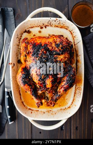 Poulet rôti vietnamien avec sauce : poulet rôti entier dans un plat de cuisson en céramique avec sauce et set de sculpture Banque D'Images