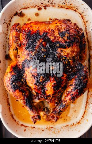 Gros plan de poulet rôti vietnamien dans un plat de cuisson : poulet rôti entier glacé brun doré dans un plat de cuisson en grès céramique blanc Banque D'Images