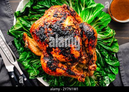 Poulet rôti vietnamien sur un lit de Bok Choy sauté : poulet rôti glacé entier brun doré sur un plateau recouvert de bok choy fané Banque D'Images