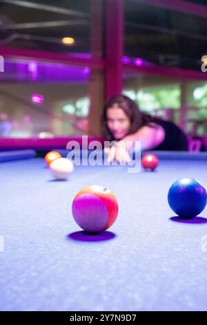 Un joueur concentré se prépare à prendre un coup impressionnant à une table de billard vibrante avec des balles colorées Banque D'Images