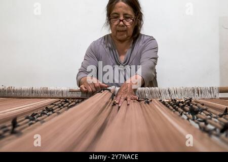 Santa Rosa, la Pampa, Arfentina - 07 novembre 2022 : femme artisanale d'âge moyen dans les Andes argentines fabriquant un poncho sur le métier à tisser traditionnel en bois, Banque D'Images