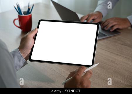 homme d'affaires vérifiant sur la tablette numérique et tenant la tablette d'écran blanc dans le bureau Banque D'Images