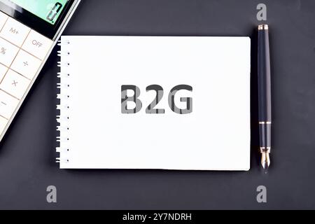 B2G - abréviation de Business to Government. B2G écrit dans un cahier, vue de dessus dans une composition avec un stylo plume et une calculatrice Banque D'Images