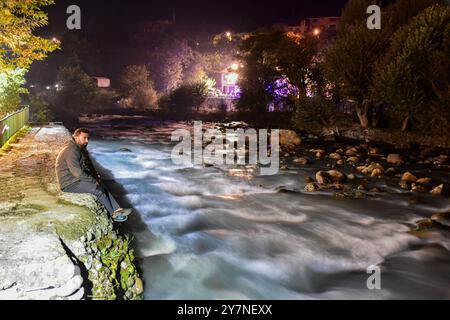 Pahalgam, Inde. 30 septembre 2024. Un visiteur pose des repose près du ruisseau sous le ciel étoilé de la nuit à Pahalgam, une station de colline à environ 120kms de Srinagar la capitale estivale du Jammu-et-Cachemire. Crédit : SOPA images Limited/Alamy Live News Banque D'Images