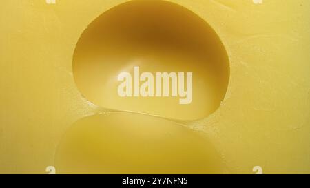 morceau de fromage gros plan , fromage jaune avec de grands trous , texture , macro photo Banque D'Images