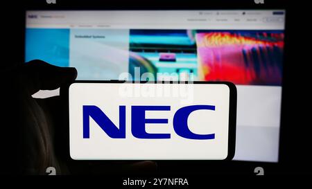 Allemagne. 26 septembre 2024. Dans cette illustration photo, une personne tient un téléphone portable avec le logo de la société japonaise de technologie de l'information NEC Corporation devant la page Web. (Crédit image : © timon Schneider/SOPA images via ZUMA Press Wire) USAGE ÉDITORIAL SEULEMENT ! Non destiné à UN USAGE commercial ! Banque D'Images