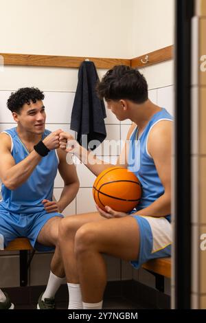 Divers joueurs de basket-ball dans les vestiaires, coups de poing et tenant le basket-ball, liaison Banque D'Images