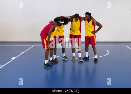 Se blottissant ensemble, les joueurs de basket-ball afro-américains élaborent une stratégie sur un terrain couvert avant le match Banque D'Images