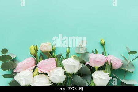 Une belle composition avec de délicates fleurs pastel aux côtés de feuilles d'eucalyptus est placée sur un fond turquoise vibrant. La Fresh Blooms cr Banque D'Images