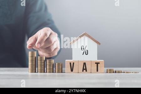 L'homme empile des pièces sur une table, les arrange du plus petit au plus grand, avec un modèle de maison en bois à côté de lui. Met l'accent sur le concept de sauver Mone Banque D'Images