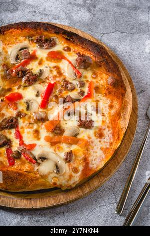 Pizza avec paprika et rôti de bœuf sur planche à découper sur table en pierre Banque D'Images