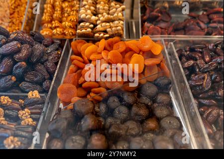 Une variété colorée de fruits secs, y compris des abricots et des figues, soigneusement arrangés pour la vente. Banque D'Images