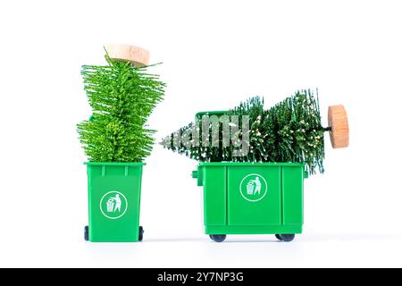 Deux poubelles vertes contenant des arbres de Noël miniatures, mettant en évidence les concepts de recyclage et de gestion des déchets. Banque D'Images