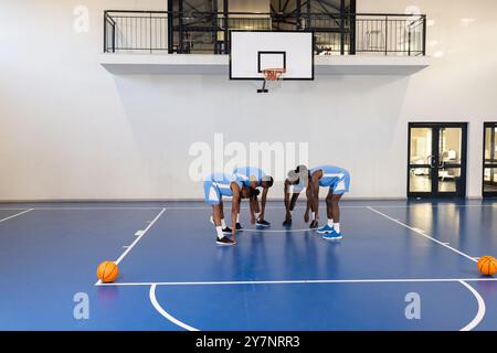 Joueurs de basket-ball se blottissant sur le terrain, se préparant pour le match, portant des uniformes bleus Banque D'Images