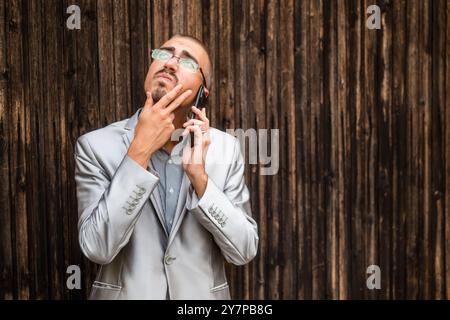 Portrait d'homme d'affaires réfléchi qui parle au téléphone. Fond en bois. Banque D'Images