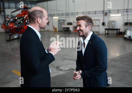 Le prince de Galles parle avec David Beckham à son arrivée à la RAF Northolt pour voir les deux nouveaux hélicoptères London Air Ambulance Charity. L'association caritative a reçu deux nouveaux hélicoptères H135 dans le cadre de l'appel de fonds « Up Against Time » lancé en 2021 et levé un total de 16 millions de livres sterling. Date de la photo : mardi 1er octobre 2024. Banque D'Images