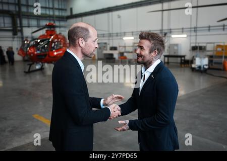 Le prince de Galles parle avec David Beckham à son arrivée à la RAF Northolt pour voir les deux nouveaux hélicoptères London Air Ambulance Charity. L'association caritative a reçu deux nouveaux hélicoptères H135 dans le cadre de l'appel de fonds « Up Against Time » lancé en 2021 et levé un total de 16 millions de livres sterling. Date de la photo : mardi 1er octobre 2024. Banque D'Images