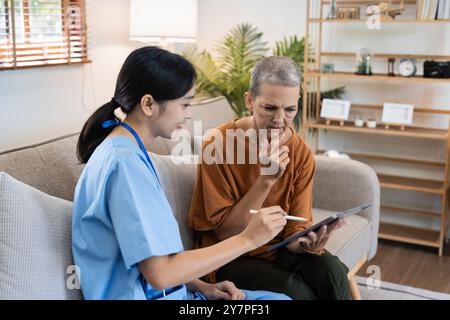 Professionnel de la santé effectuant une visite à domicile pour femme senior, fournissant une consultation médicale et un soutien dans un cadre confortable salon Banque D'Images