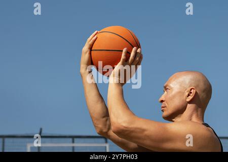 Joueur de basket-ball ou l'homme essaie de jeter la balle dans le panier de basket-ball sur le terrain de sport. Moment de jeu. Entraînement en plein air d'été. Basket-ball lancer Techniqu Banque D'Images