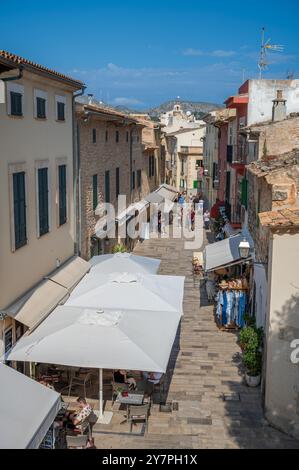 Une rue pittoresque dans une ville avec des cafés en plein air et des boutiques par une journée ensoleillée à Alcudia, Majorque Banque D'Images