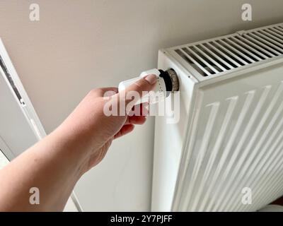 La main d'une femme commute la température sur le radiateur. Gros plan du radiateur. Le début de la saison de chauffage, chauffage de la pièce. Banque D'Images