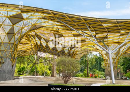 Jardin botanique de Perdana, Kuala Lumpur, Malaisie avec une structure architecturale moderne avec un toit géométrique jaune et un grand espace ouvert entouré par Banque D'Images