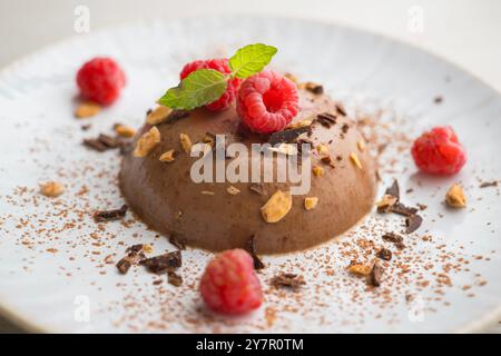 Flan au chocolat noir aux amandes. Décoré de poudre de cacao et de framboises. Banque D'Images