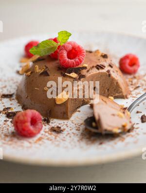 Flan au chocolat noir aux amandes. Décoré de poudre de cacao et de framboises. Banque D'Images