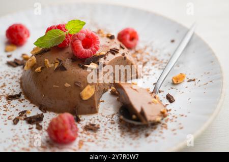 Flan au chocolat noir aux amandes. Décoré de poudre de cacao et de framboises. Banque D'Images