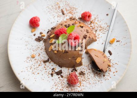 Flan au chocolat noir aux amandes. Décoré de poudre de cacao et de framboises. Banque D'Images