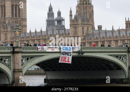 Londres, Royaume-Uni. 1er octobre 2024. Les militants contre la pauvreté énergétique effectuent un largage de bannière sur le pont de Westminster, programmé pour coïncider avec une hausse des prix de l’énergie approuvée par l’OFGEM (Office of Gas and Electricity Markets), le régulateur gouvernemental des marchés de l’électricité et du gaz. Les prix typiques de l'énergie augmentent de 10 % aujourd'hui et font suite à la suppression controversée de l'allocation de carburant d'hiver qui touche des millions de retraités. L'action faisait partie d'une série de manifestations nationales appelant à la propriété publique de la production d'énergie et du carburant abordable. Crédit : Ron Fassbender/Alamy Live News Banque D'Images