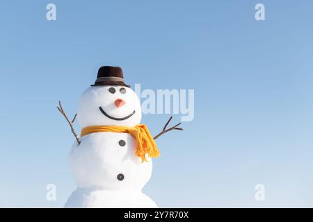 Bonhomme de neige drôle dans un élégant chapeau brun et scard jaune. Ciel bleu clair sur fond Banque D'Images