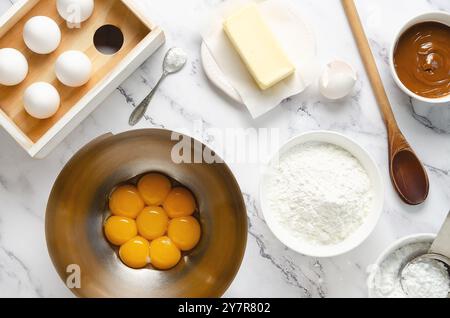 Préparation des ingrédients pour faire des biscuits et des alfajores d'amidon de maïs. Oeufs, jaunes d'oeufs dans un bol, beurre, amidon de maïs, sucre en poudre, levure chimique. Banque D'Images