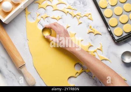 Couper la pâte pour faire des biscuits et des alfajores d'amidon de maïs sur un fond de marbre blanc. Banque D'Images