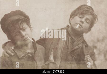 Photo vintage de deux garçons posant avec des cigarettes. Carte postale photographique de A. Caggiano, années 1900 Banque D'Images