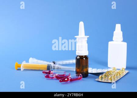 Pharmacien. Bouteilles de gouttes médicales, ampoules de pilules et seringues sur fond bleu Banque D'Images