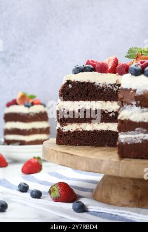 Délicieux gâteau éponge au chocolat avec des baies servi sur une table blanche Banque D'Images