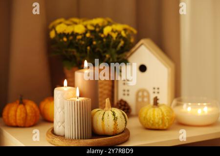 Bougies allumées, citrouilles et décor d'automne sur la table blanche Banque D'Images