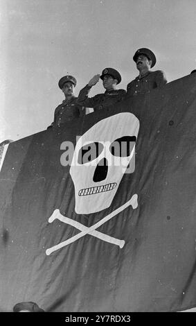 QUI EST LE PIRATE ? Négouib prend le salut sur le crâne et les os croisés. Le 23 janvier 1954 marquait le premier anniversaire de la libération en Egypte. Au Caire, le président égyptien, le général Négouib, a organisé son plus grand défilé à ce jour - de 35 000 miliciens volontaires. Parmi ceux-ci figuraient trois cents sten gun girls vêtues d'une robe de combat vert olive. Le général Négouib a pris le salut d'un stand spécialement érigé sur la place républicaine, drapé d'un énorme crâne rouge et blanc et d'os croisés. La photo de l'I.N.P. montre le général Néguib prenant le salut sur le stand spécialement érigé sur la place républicaine. 453/SP Banque D'Images