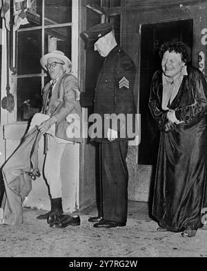 Le rire est sur lui - mais le pantalon ne l'est pas. Le 16 septembre 1953, John Guilfoy a du mal à se mettre dans son pantalon après un récent incendie dans un hôtel, lorsque les flammes ont forcé les locataires à fuir dans tout ce qu'ils portaient à l'époque. MRS Leota Emahiser rit hystérique des ennuis de son voisin, tandis que le sergent de police Frank Hughs prête main forte pour mener à bien l'opération. Photo de San Francisco, Californie. Photos d'actualités internationales. Banque D'Images
